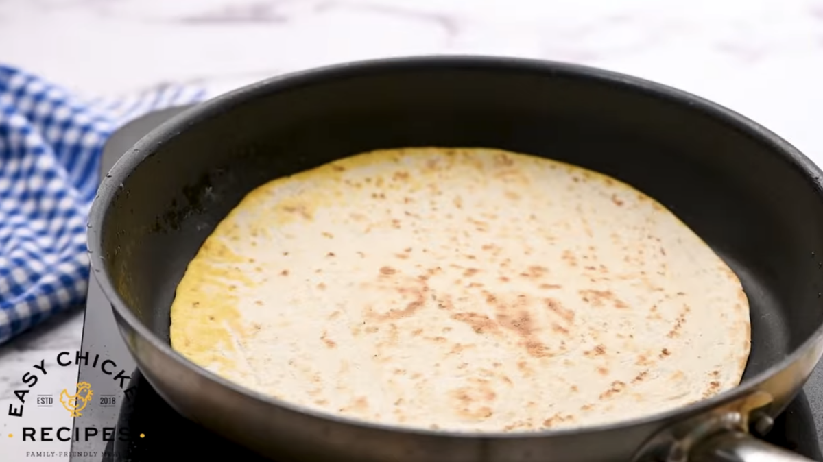 A toasted tortilla is in a skillet. 