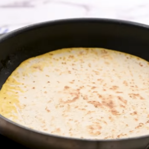 A toasted tortilla is in a skillet.