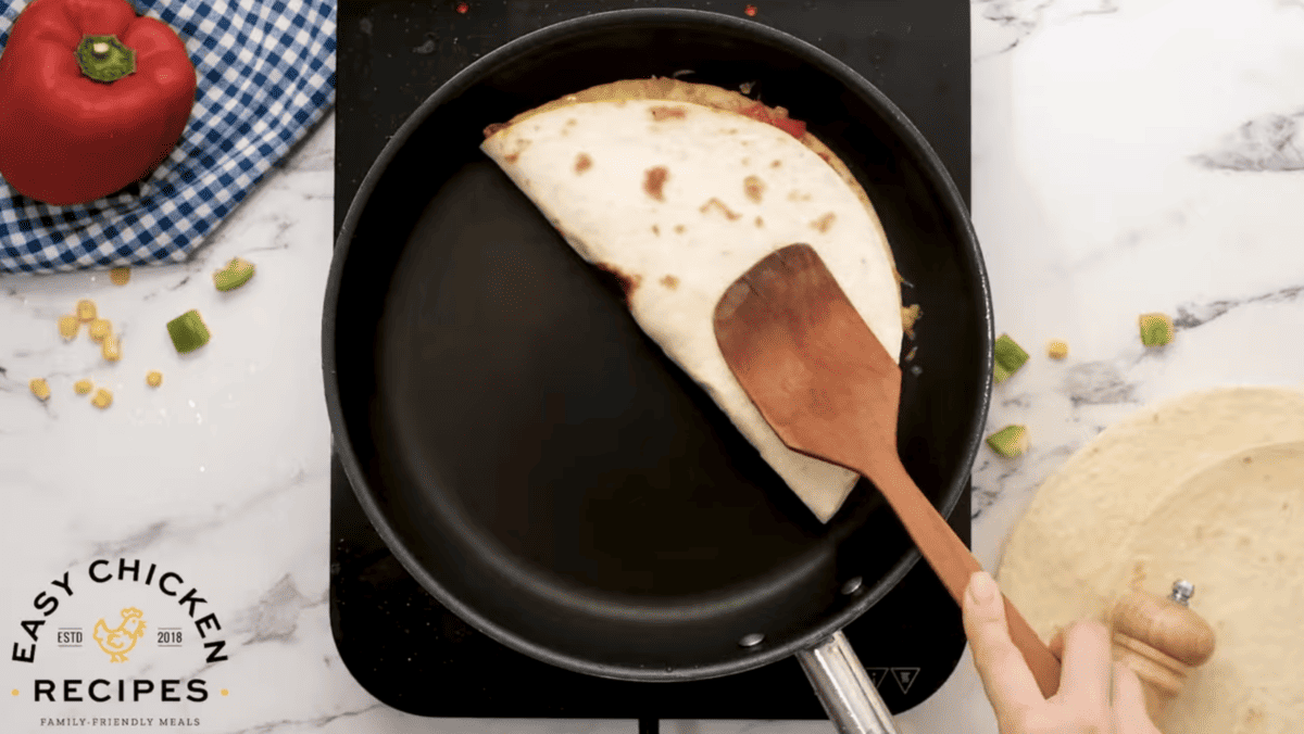 A chicken quesadilla is being cooked in a pan. 