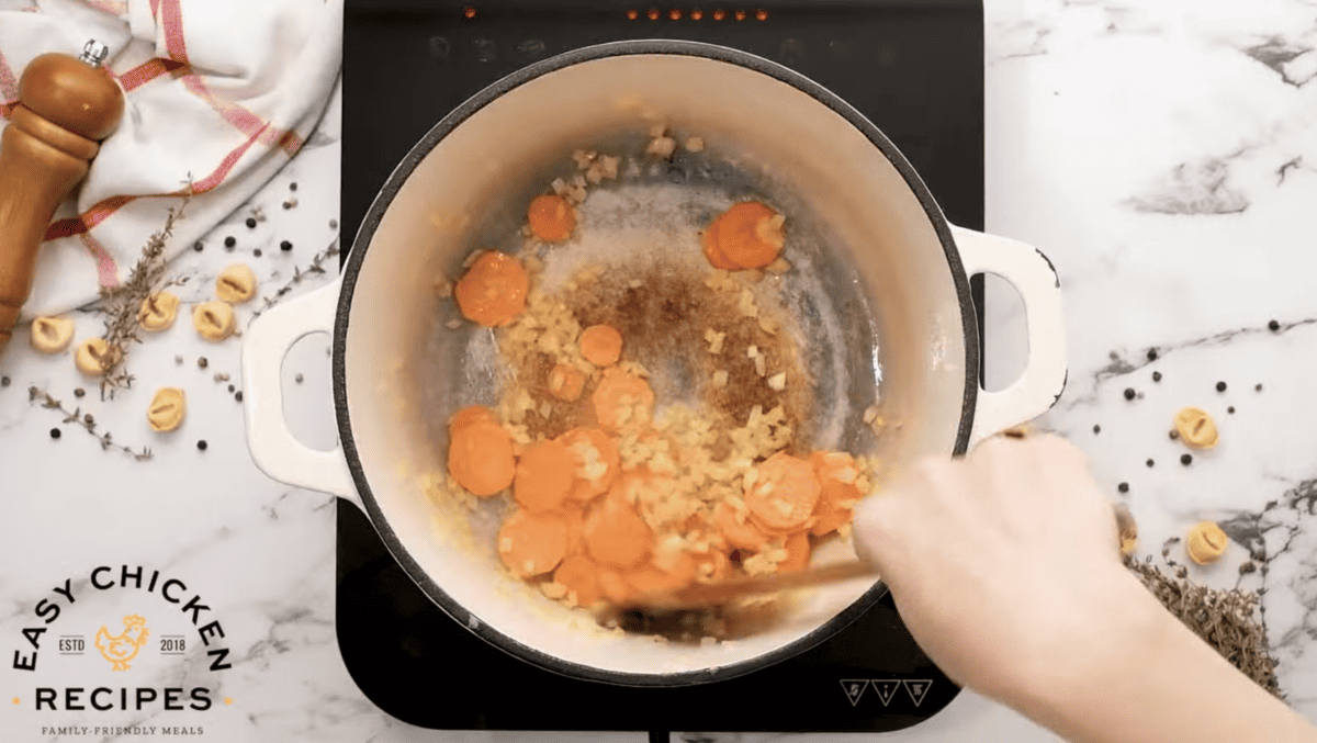 Carrots and onions are cooking in a pot.