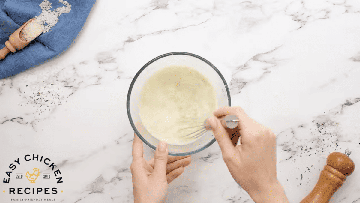 A milk and cornstarch mixture is being whisked in a bowl. 