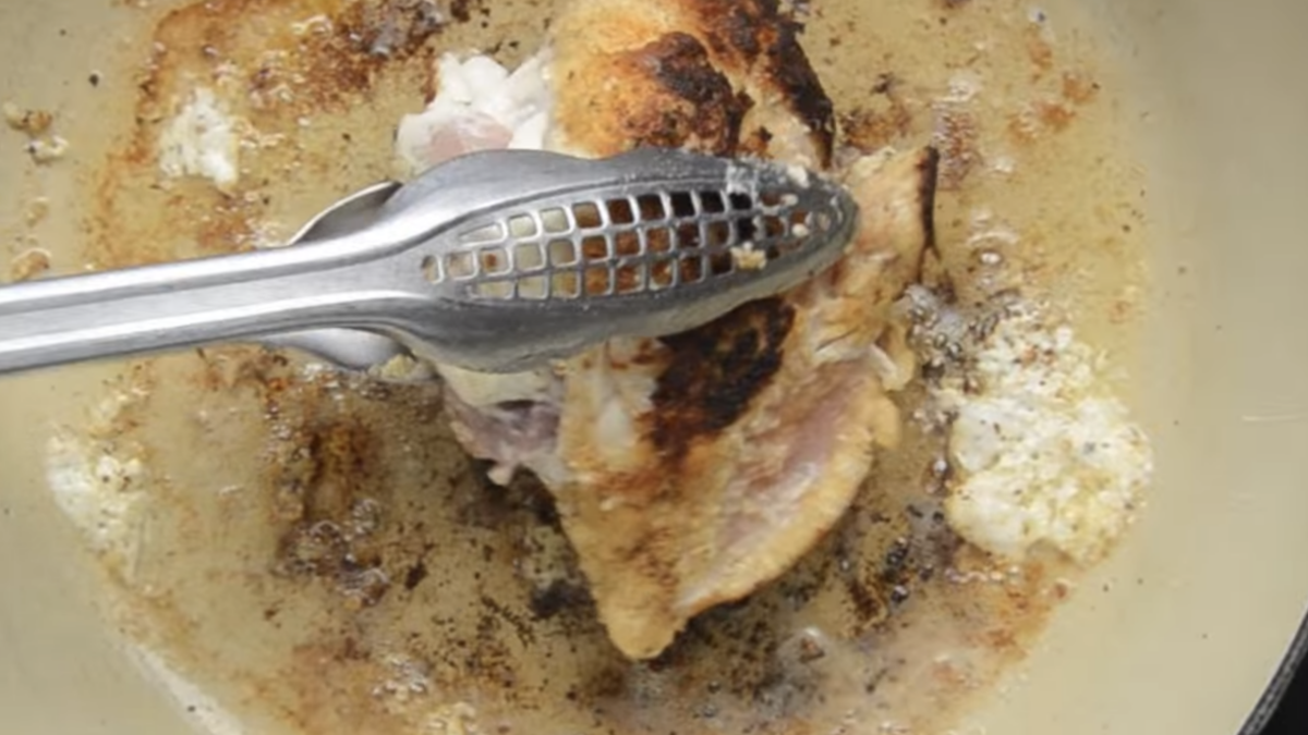 A stuffed chicken breast is being seared in a pan.