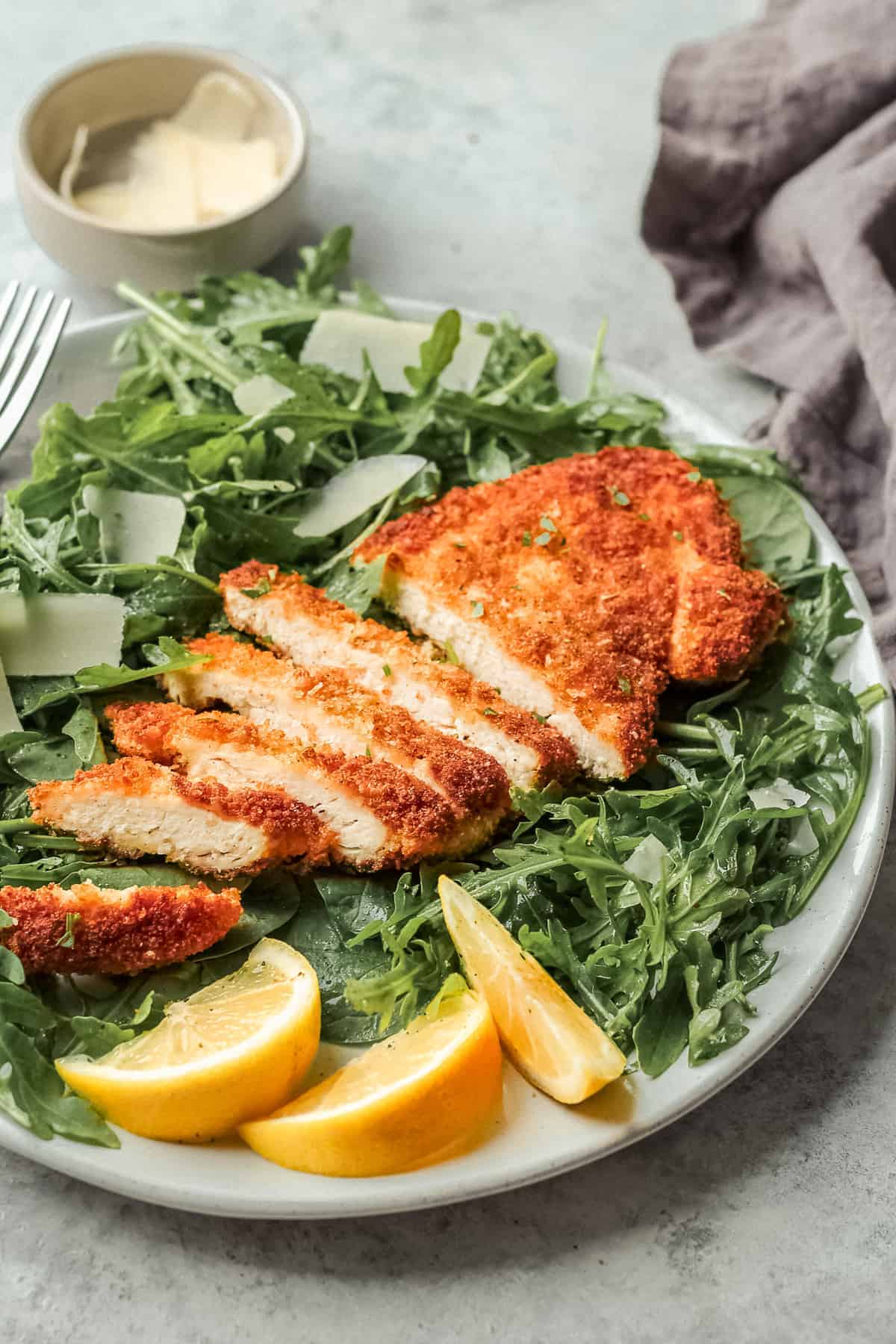 side shot of plate with salad and chicken with lemon