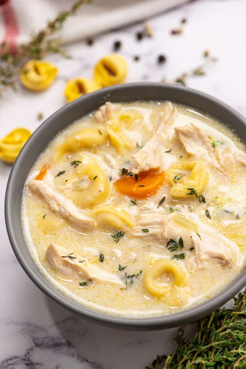 up close image of creamy chicken tortellini soup in gray bowl