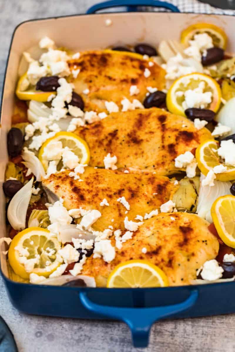 hummus crusted chicken garnished with feta, olives, artichoke hearts, and lemon