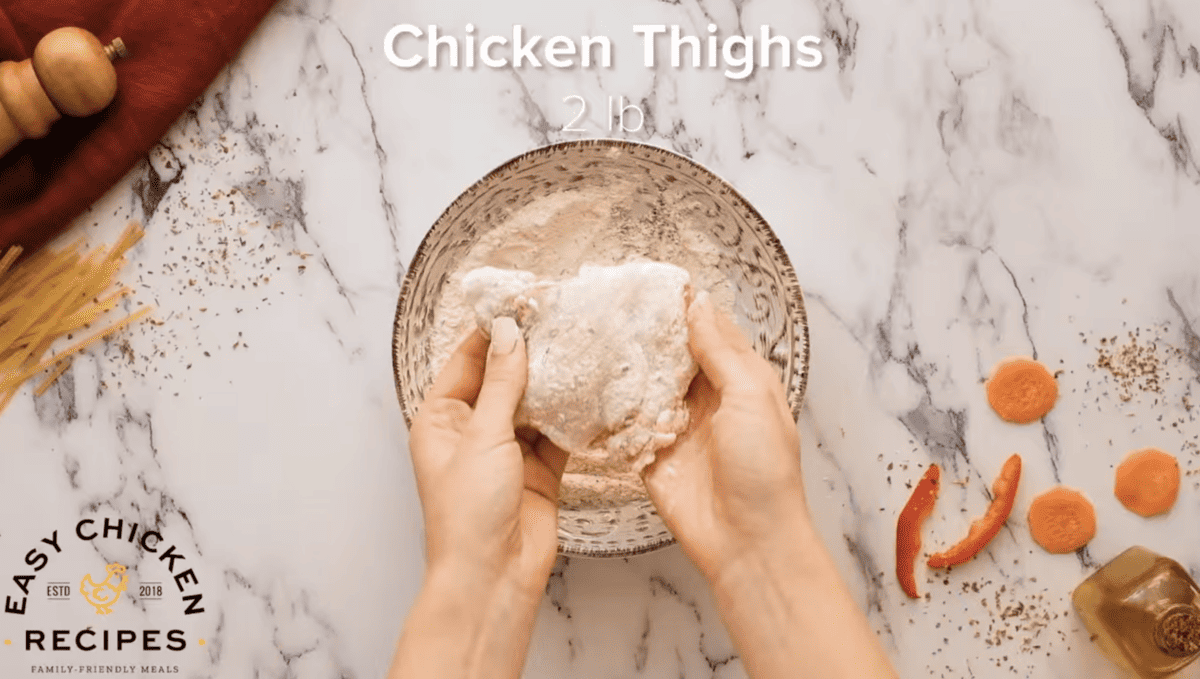 Chicken thighs are being coated in flour. 