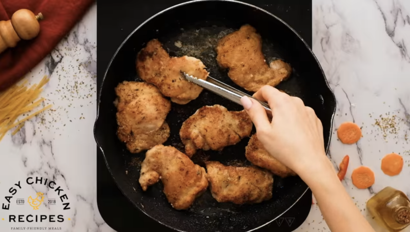 Chicken thighs are being seared in a skillet.