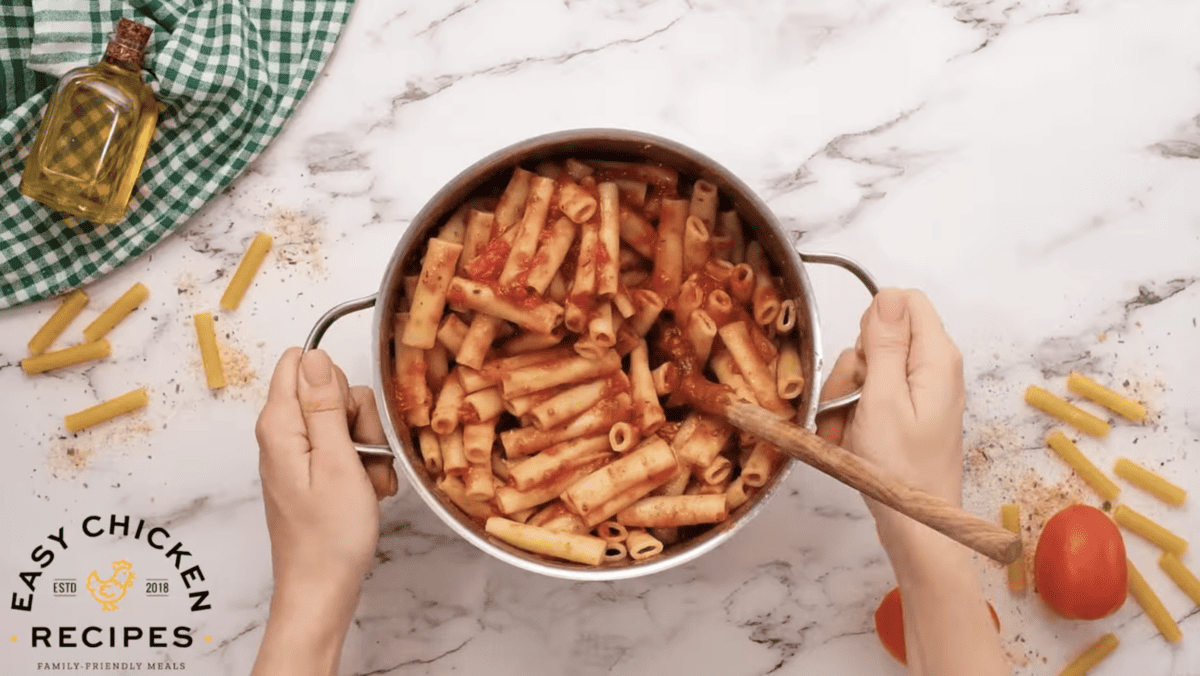 Pasta is being mixed with marinara sauce in a pot. 