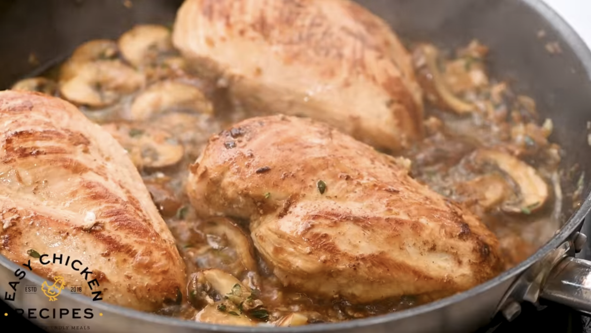Chicken breasts are cooked in a pan with the mushroom mixture.