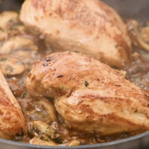 Chicken breasts are cooked in a pan with the mushroom mixture.