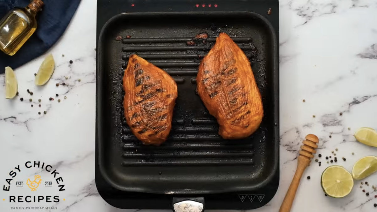 Grilled chicken breasts are on a grill. 