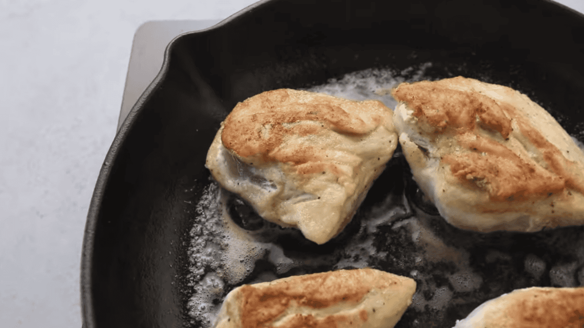Seared chicken breasts are in a skillet. 