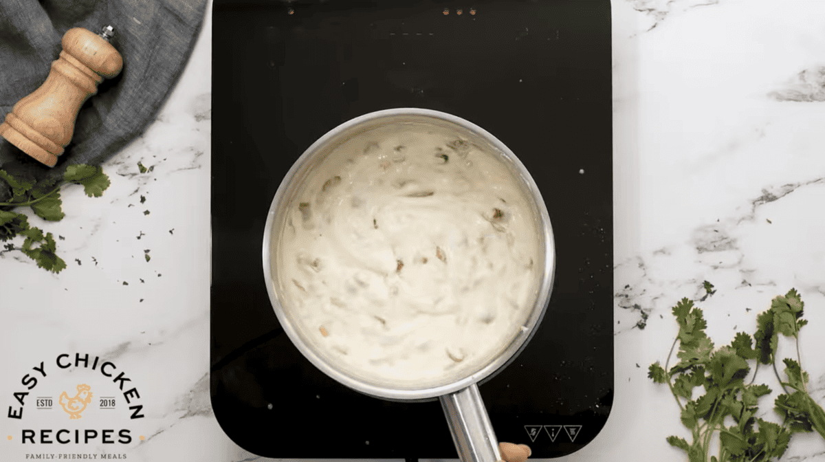 A cheesy sauce is being cooked in a small pot. 