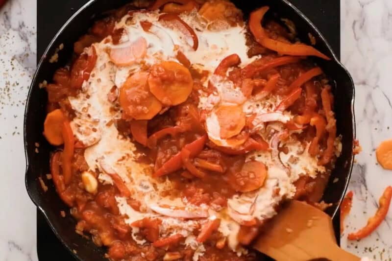 adding cream to cacciatore sauce in a pan.