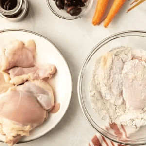 dredging chicken thighs in seasoned flour.