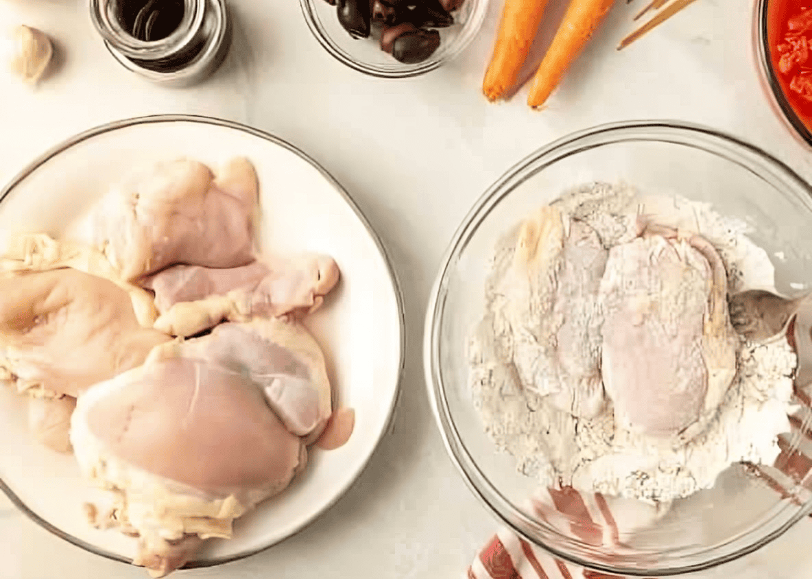 dredging chicken thighs in seasoned flour.