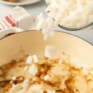 adding chopped onion to a dutch oven.