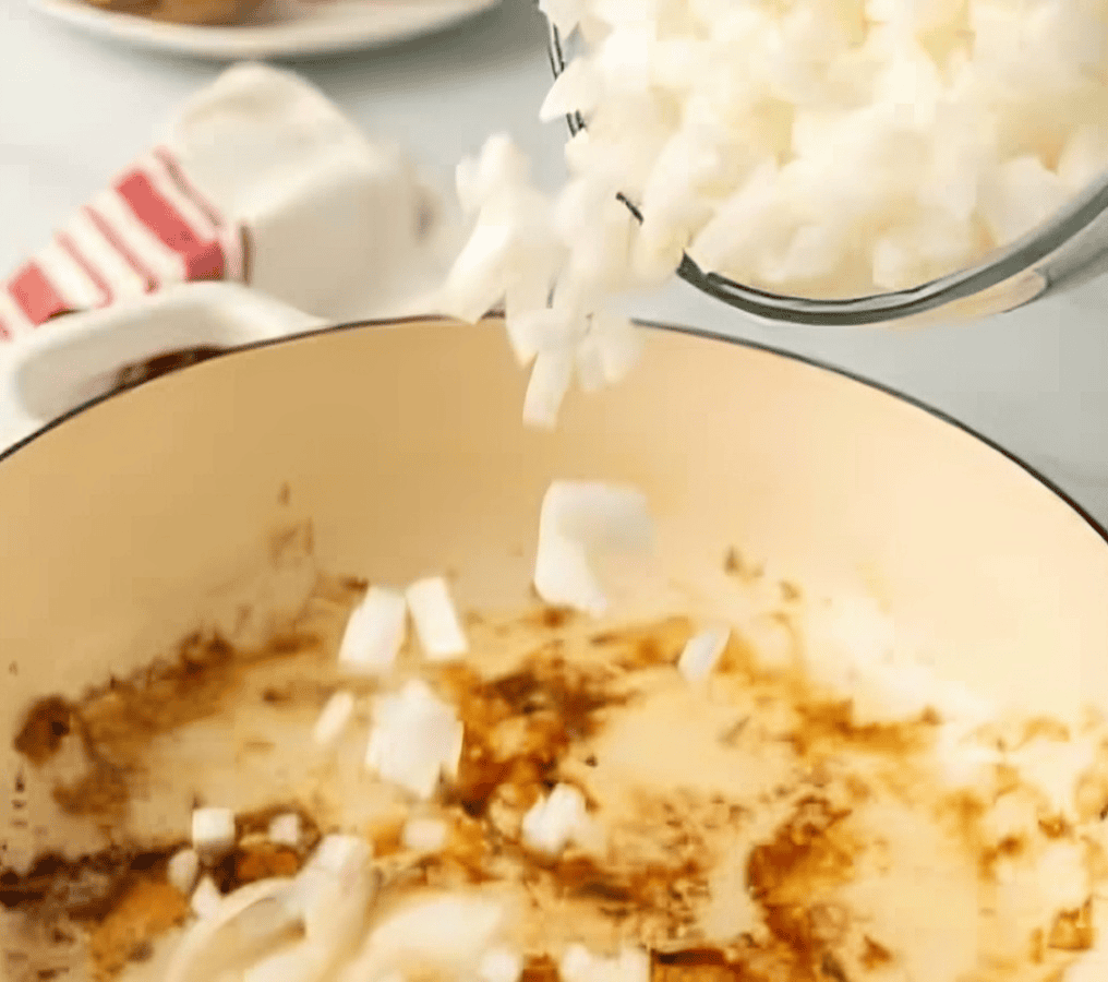 adding chopped onion to a dutch oven.