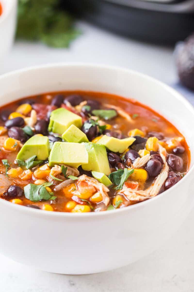 up close side shot of chicken chili garnished with avocado chunks