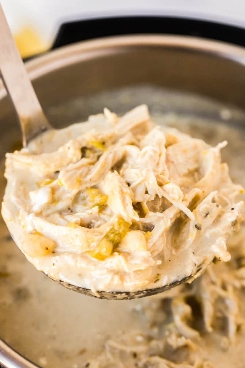 dipping spoon of white chicken chili out of instant pot