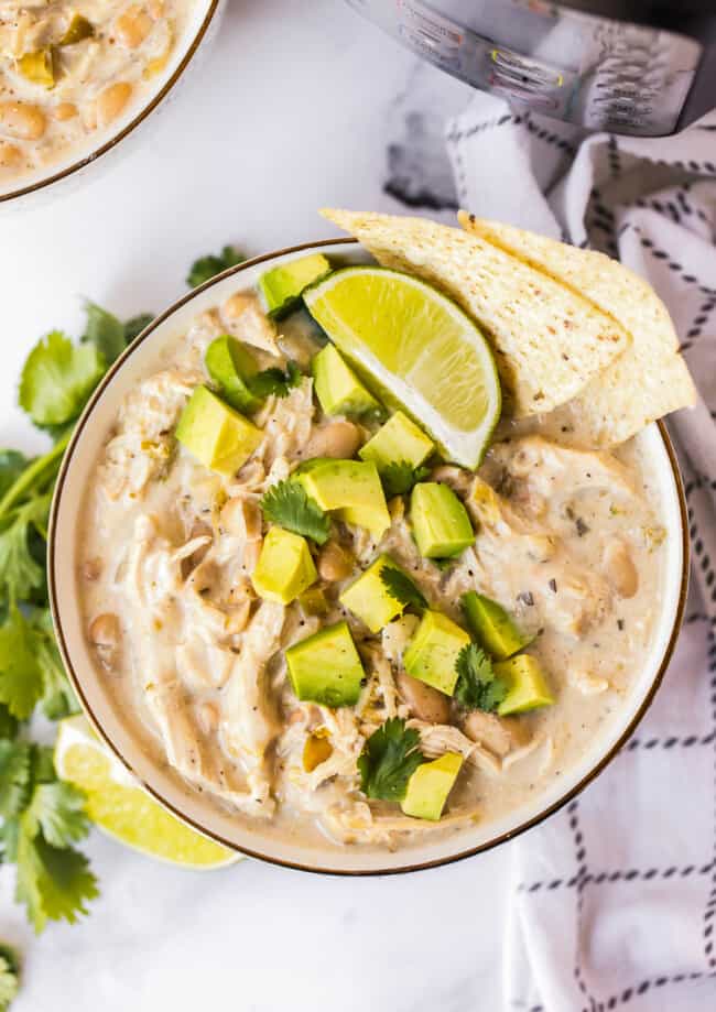 bowl of instant pot white chicken chili garnished with avocado and chips