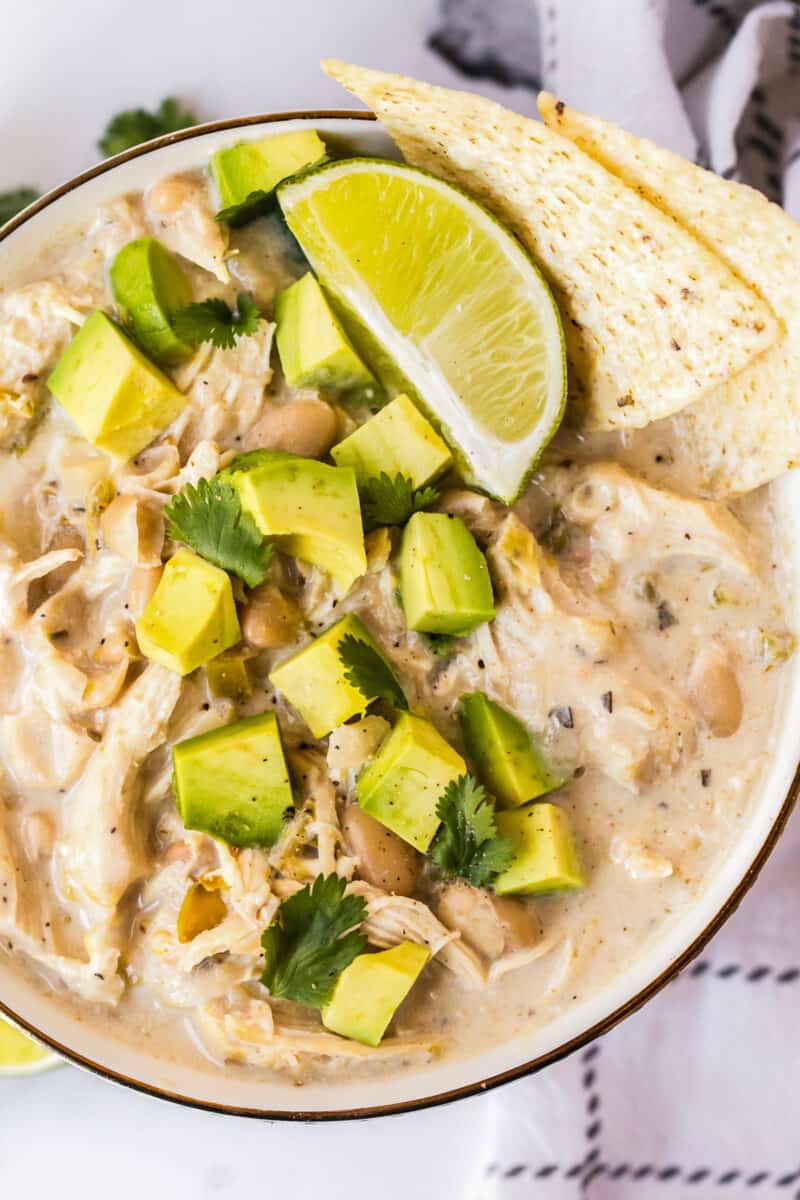 up close image of bowl of instant pot white chicken chili garnished with avocado and chips