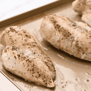 Apple-spiced chicken breasts on a baking sheet.