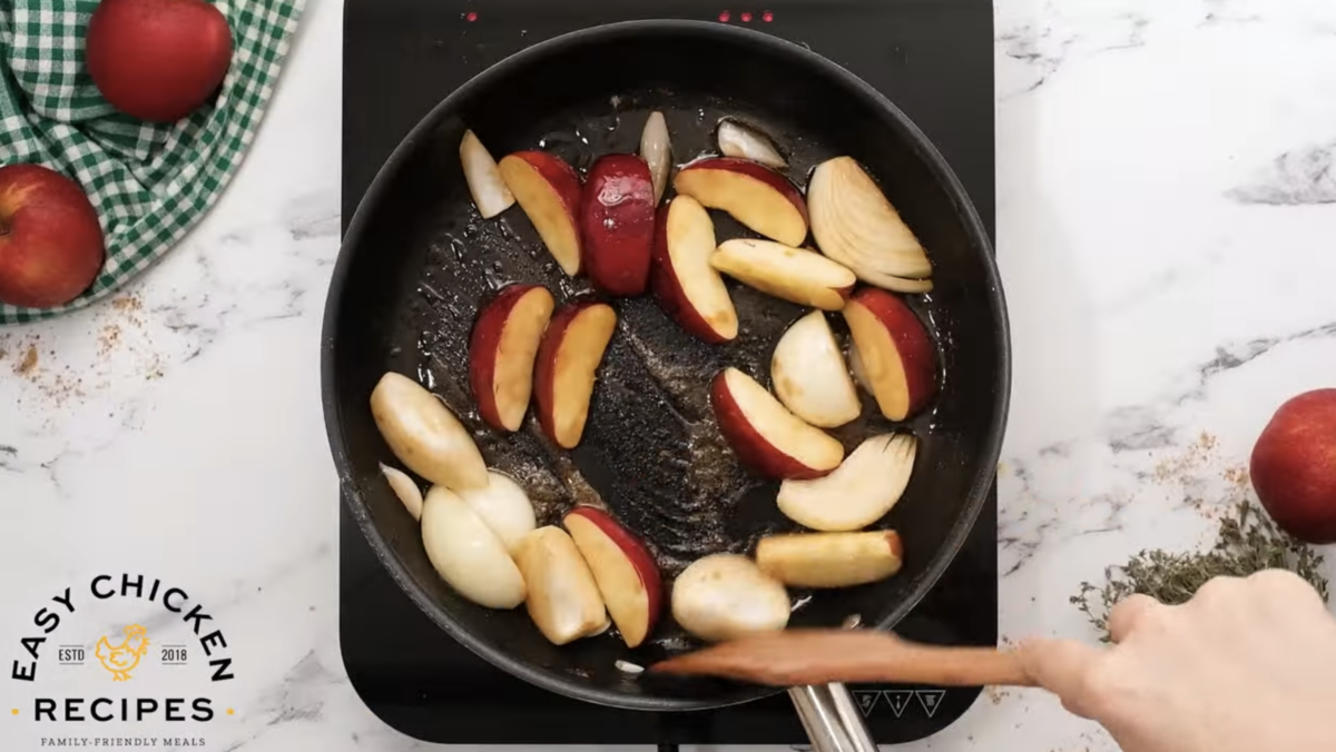Apples and onions are cooking in a skillet. 