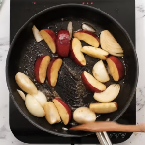 Apples and onions are cooking in a skillet.