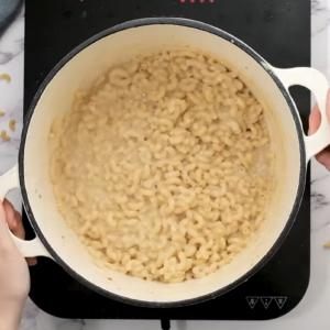 A pot is filled with cooked macaroni in a creamy sauce.