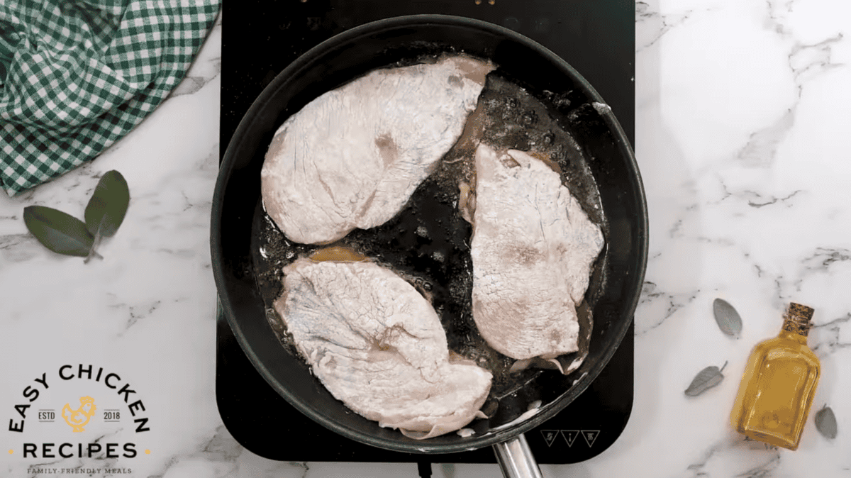 Dredged chicken is being cooked in a pan. 