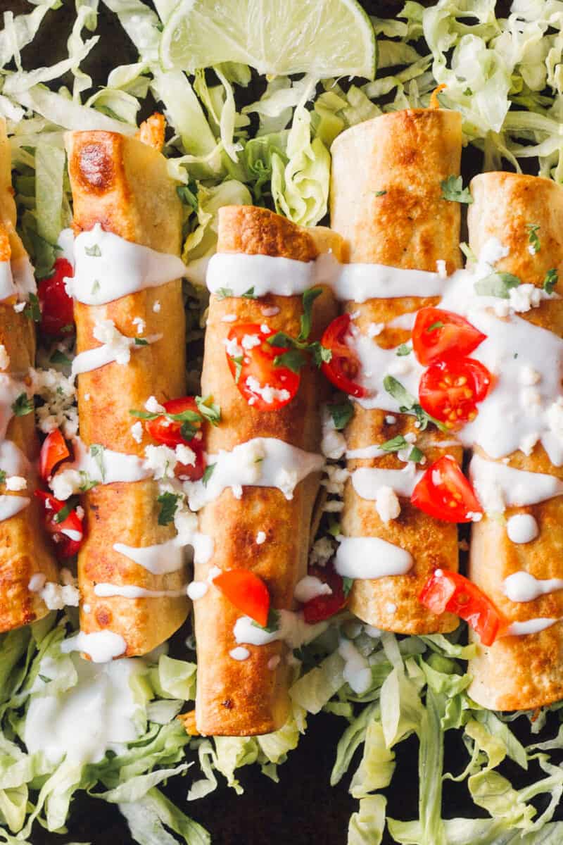 up close image of flautas garnished with pico and sour cream