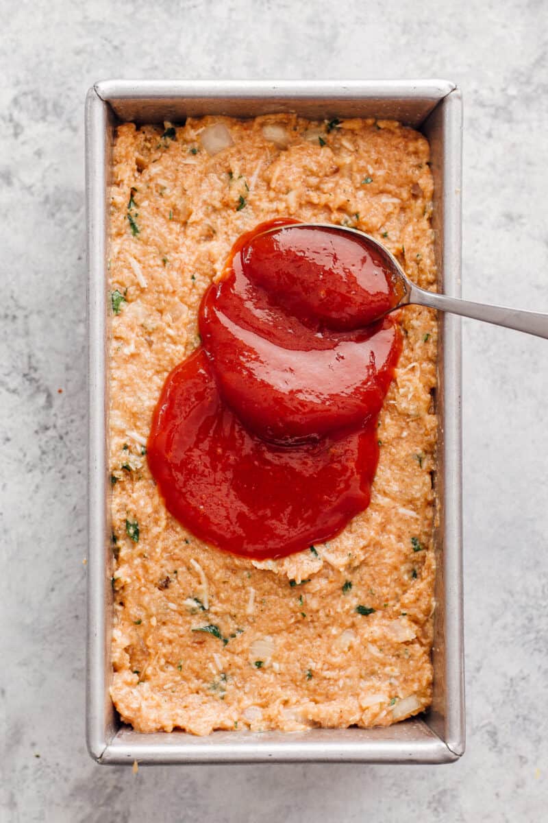 spreading sauce on chicken meatloaf