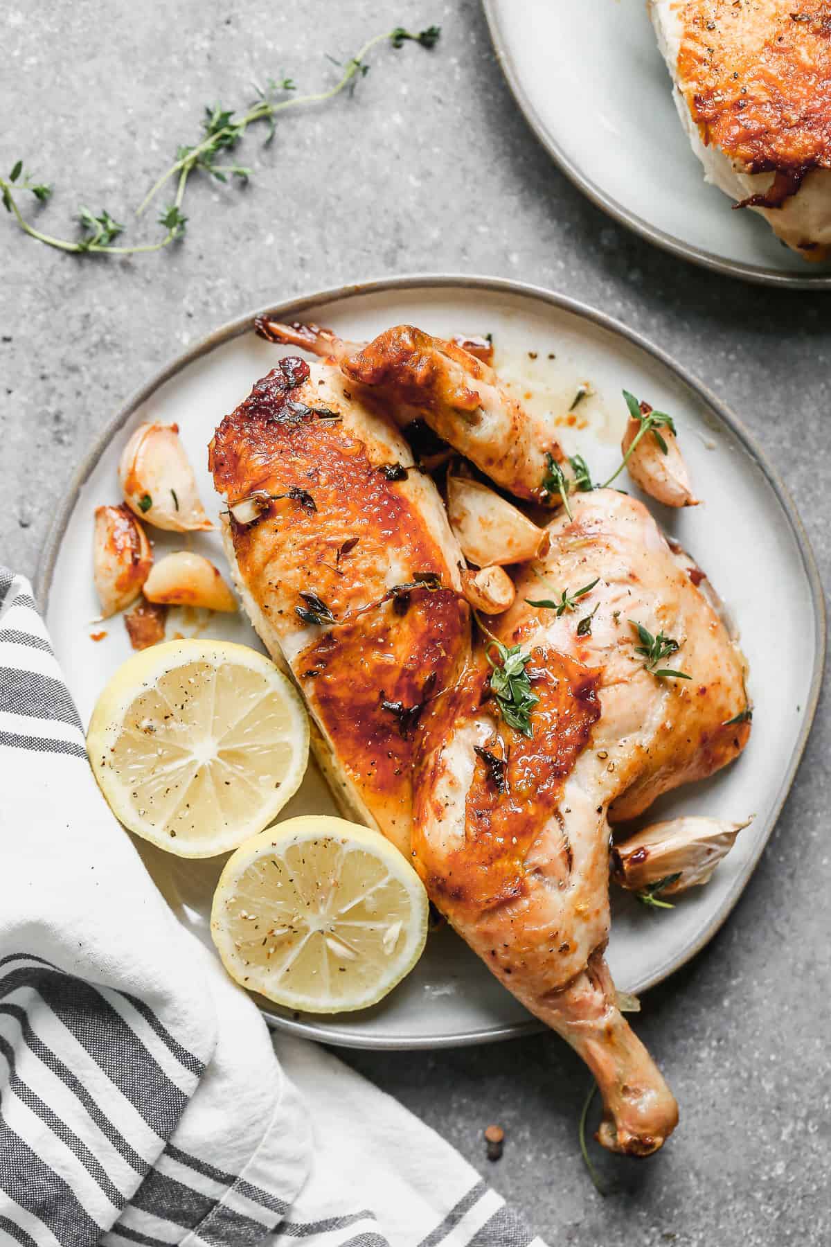 chicken under a brick on plate with lemon and parsley