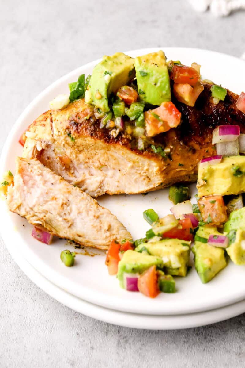 chicken breast sliced on plate topped with avocado salsa