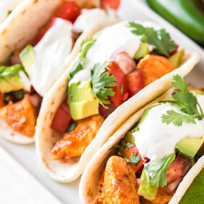 easy chicken tacos topped with avocado and sour cream