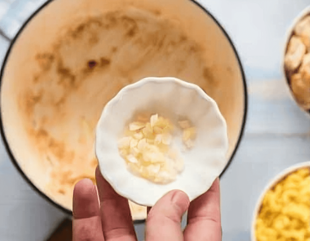 adding minced garlic to a pot.