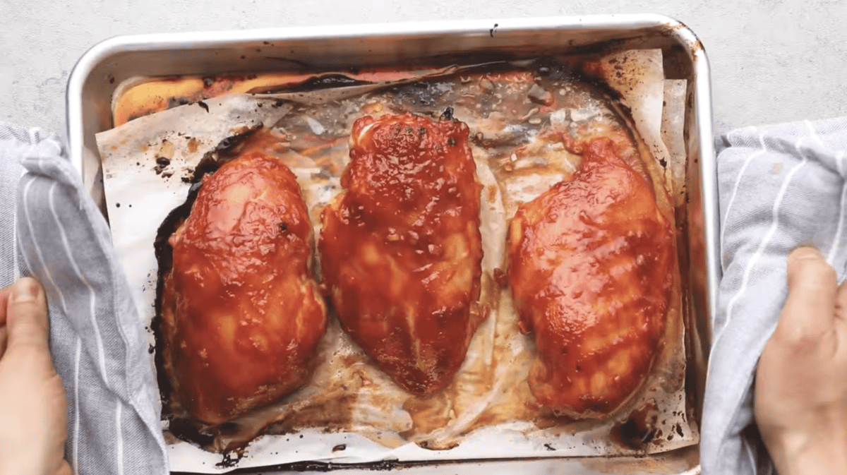 Baked chicken breasts are on a baking sheet. 