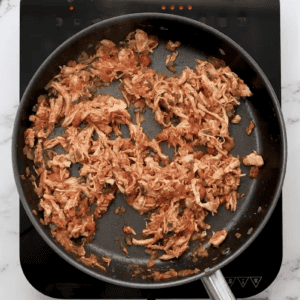 Chicken flauta filling is cooking in a skillet.