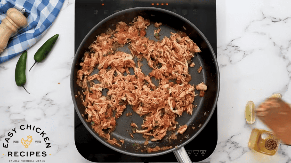 Shredded chicken cooking in a skillet.