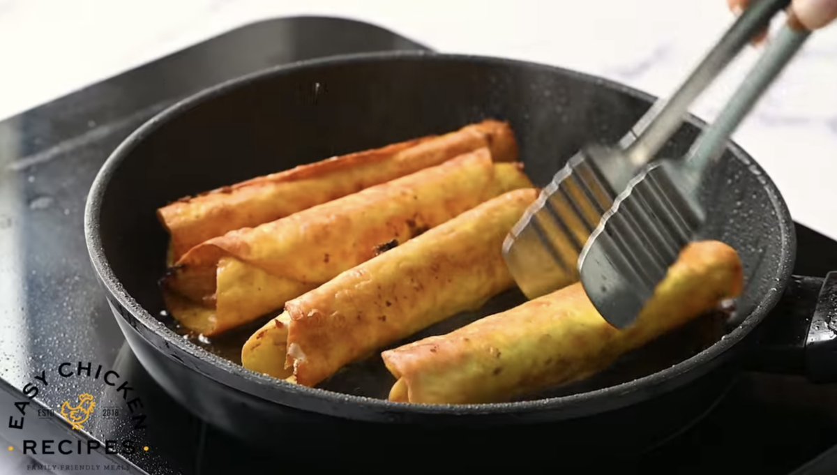 Flautas are cooking in a pan. 