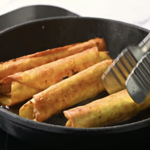 Flautas are cooking in a pan.