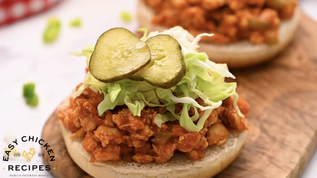 Shredded cabbage and pickles are placed on top of a chicken sloppy joe. 
