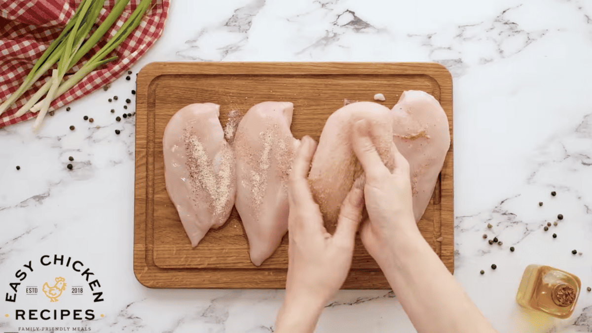 Chicken breasts are being seasoned. 