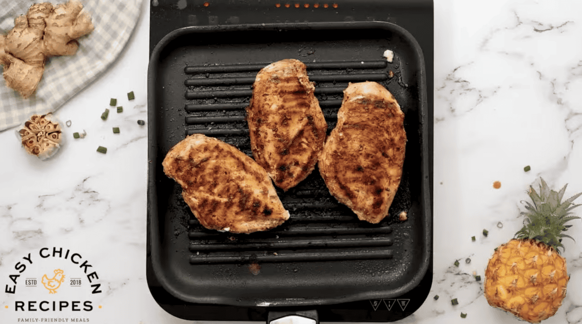 Chicken breasts are on a grill. 