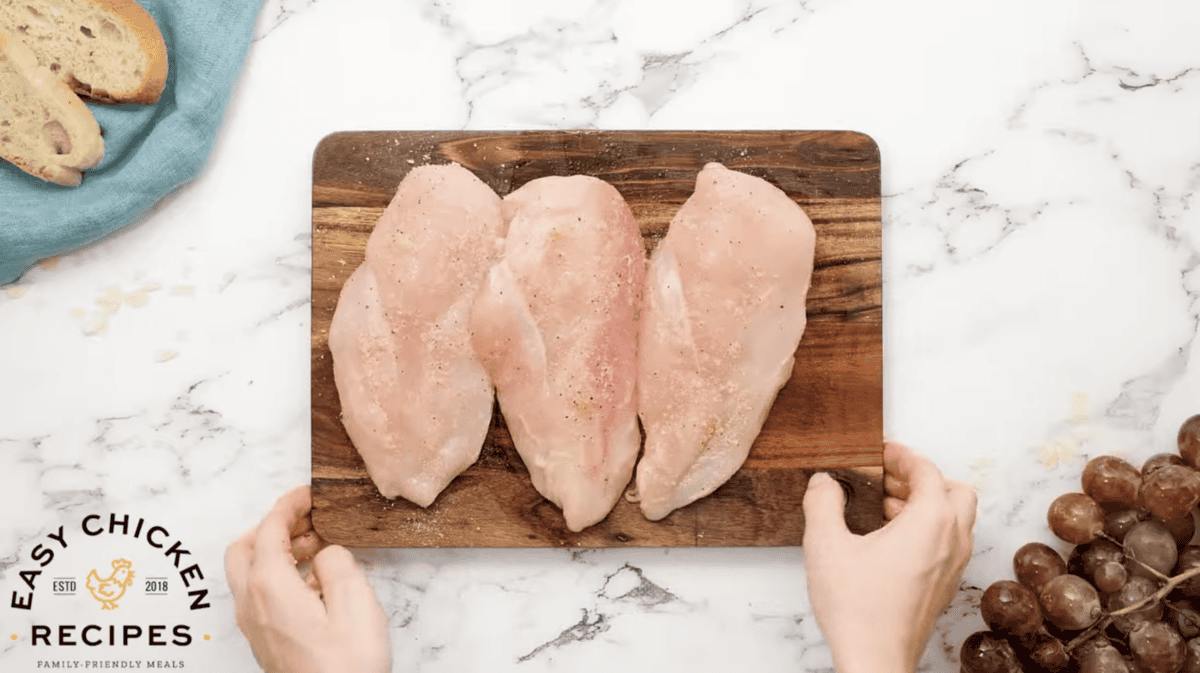 chicken breasts are seasoned on a cutting board