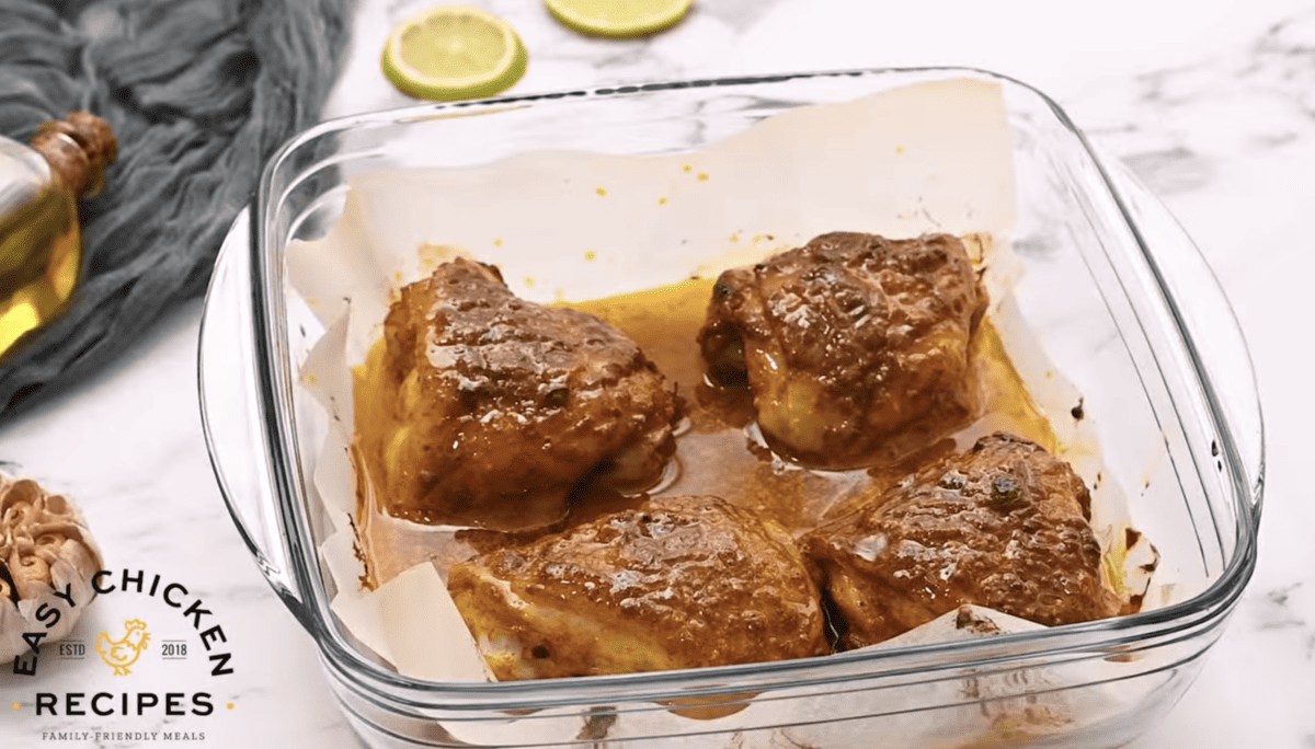 Baked Tandoori chicken thighs are in a glass dish. 