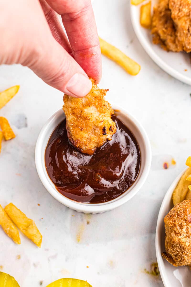 dipping air fried chicken nugget in bbq sauce