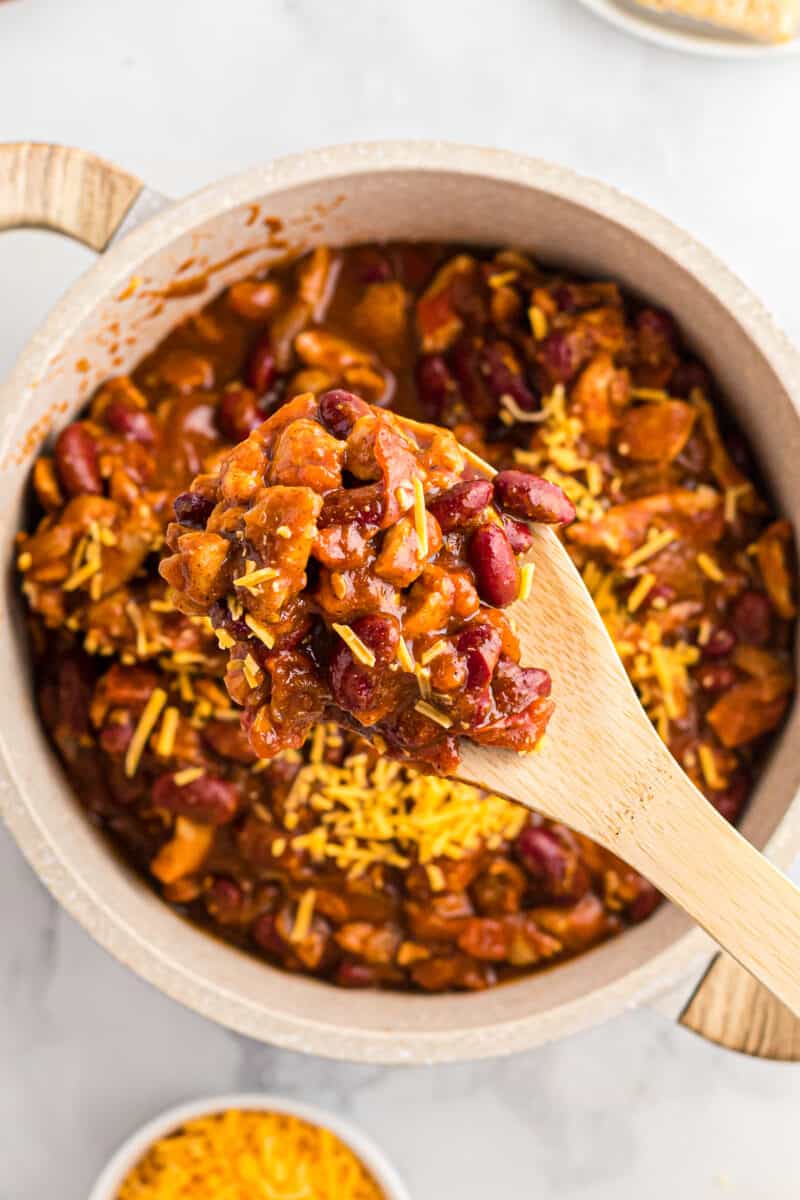 lifting up spoonful of chicken chili with cheese