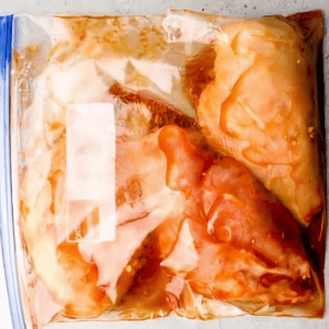 chicken breasts marinating in bbq sauce in a ziplock bag.